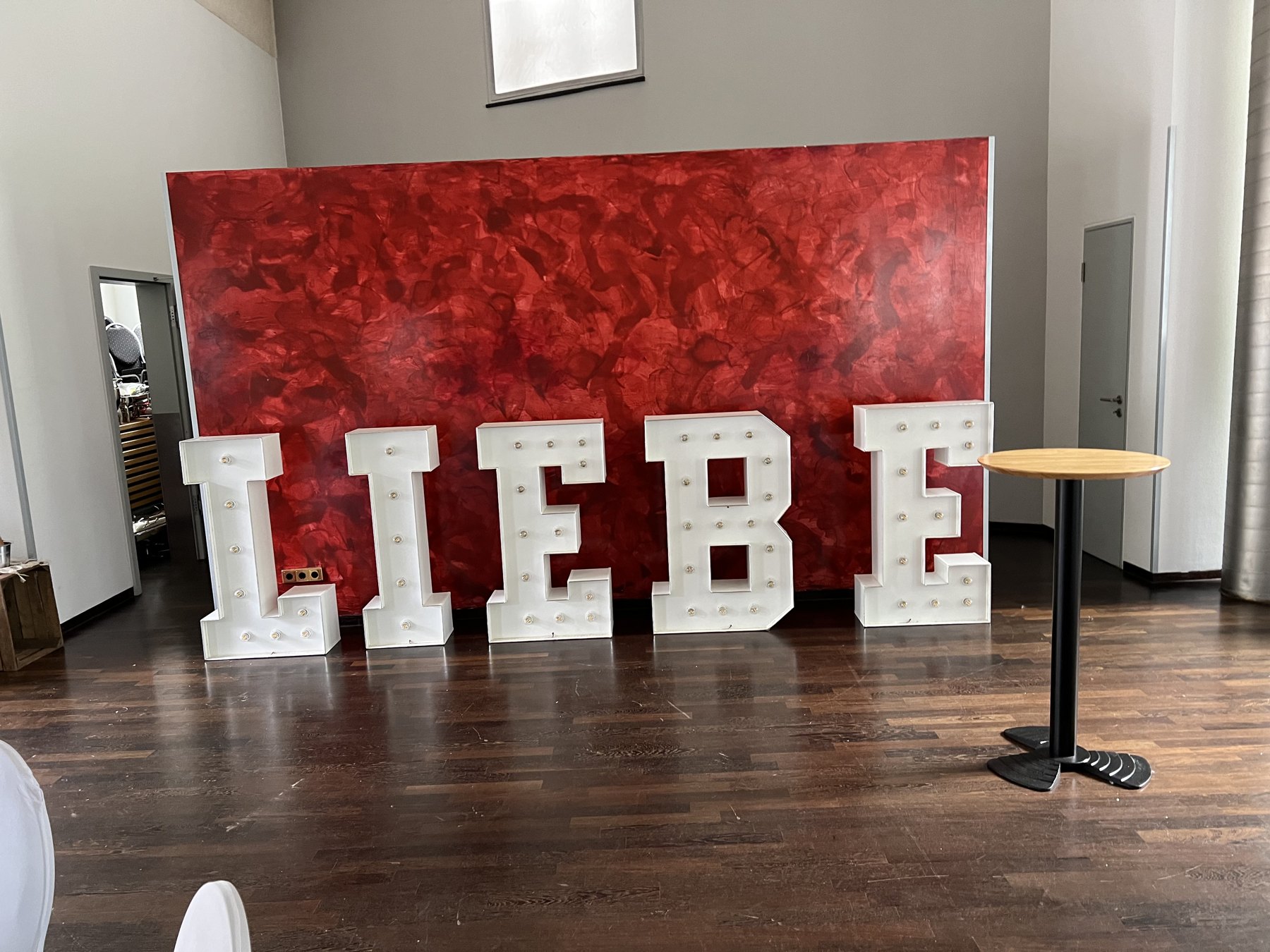 Weiße LIEBE-Buchstaben vor einer roten Blumenwand